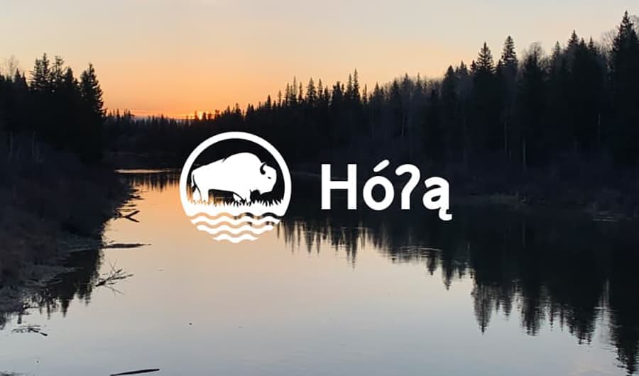 A calm river at sunset with the BRDN bison logo and the Dene word Hó?ą, meaning welcome